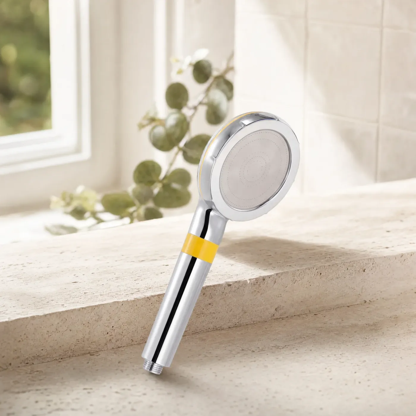Marova filtered shower head with a yellow band, resting on a stone ledge by a window